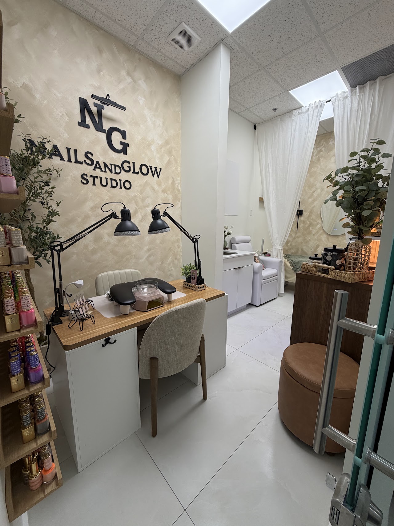 Upscale boutique nail salon sanctuary interior in Hialeah Gardens with arched walls, bouclé armchairs, minimalist manicure stations, warm wooden beams, and soft natural sunlight filtering across cream surfaces